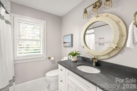 a bathroom with a granite countertop toilet a sink and a mirror
