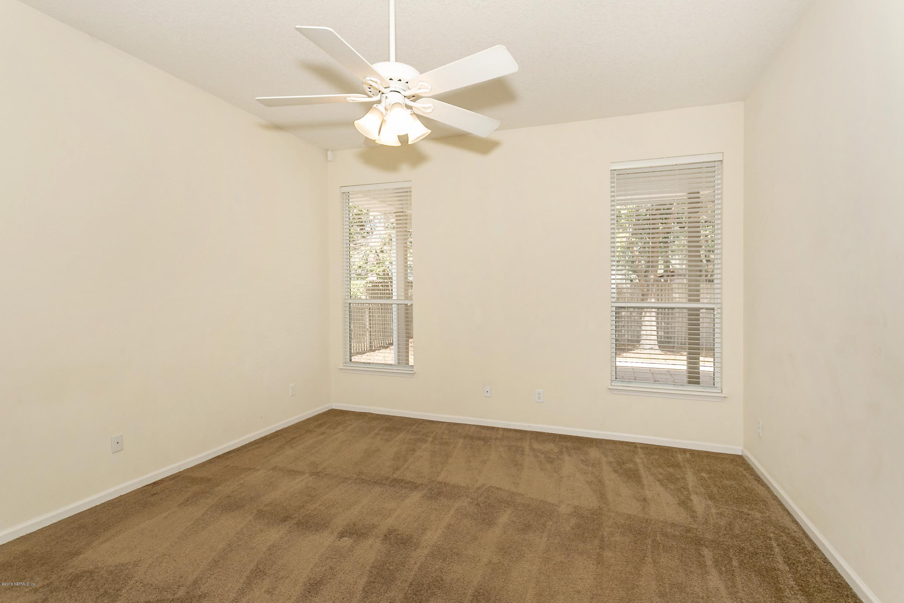2809 Hidden Stagecoach Road Jacksonville, FL 32223 - Photo 14 of 25 an empty room with a chandelier fan and windows