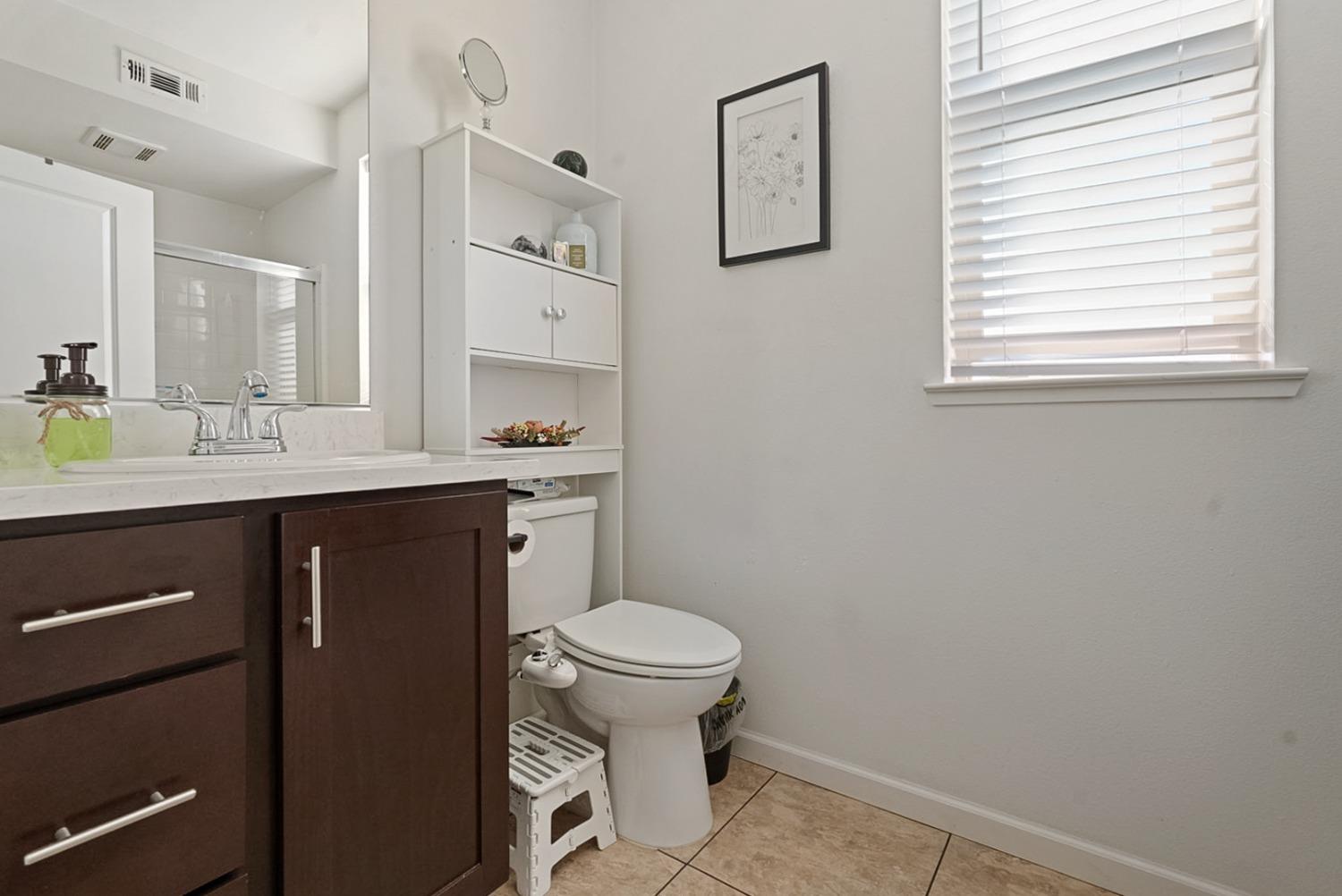 140 Ivy Avenue, Unit A5 Patterson, CA 95363 - Photo 15 of 26 a bathroom with a granite countertop toilet a sink a mirror and a window