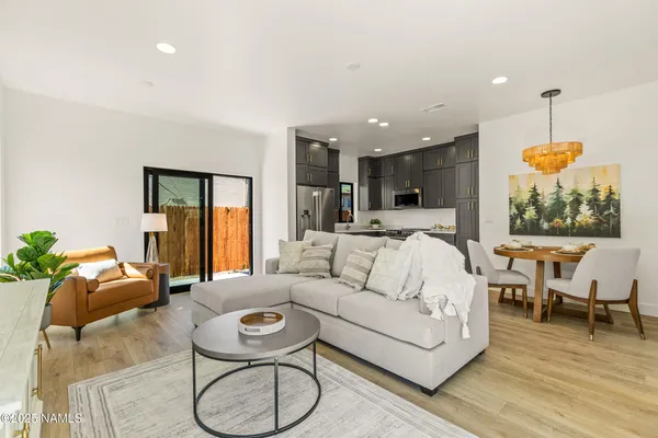 a living room with furniture kitchen view and a wooden floor