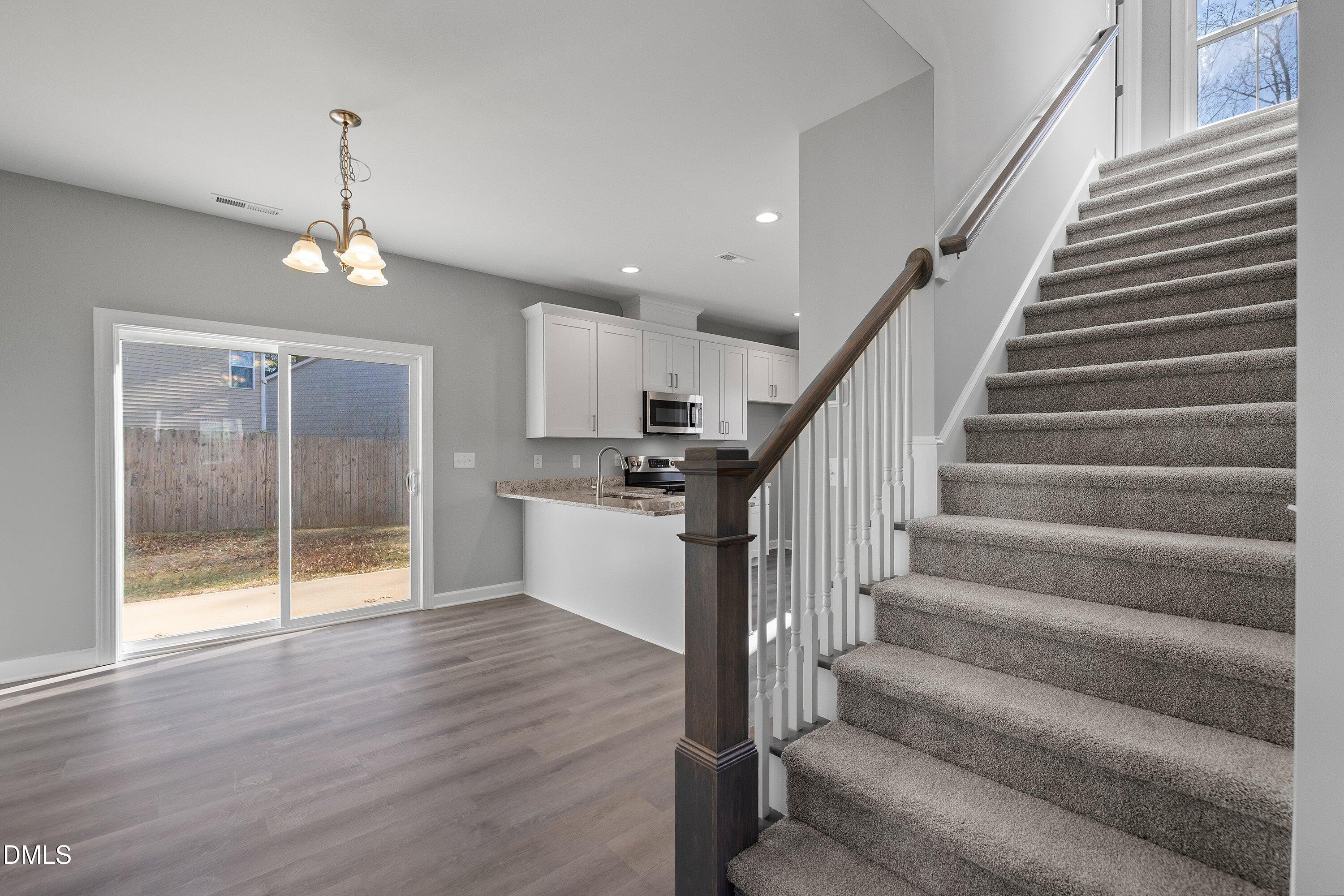 1808 Falls Landing Drive Raleigh, NC 27614 - Photo 4 of 23 a view of staircase and kitchen with wooden floor and pendant lights