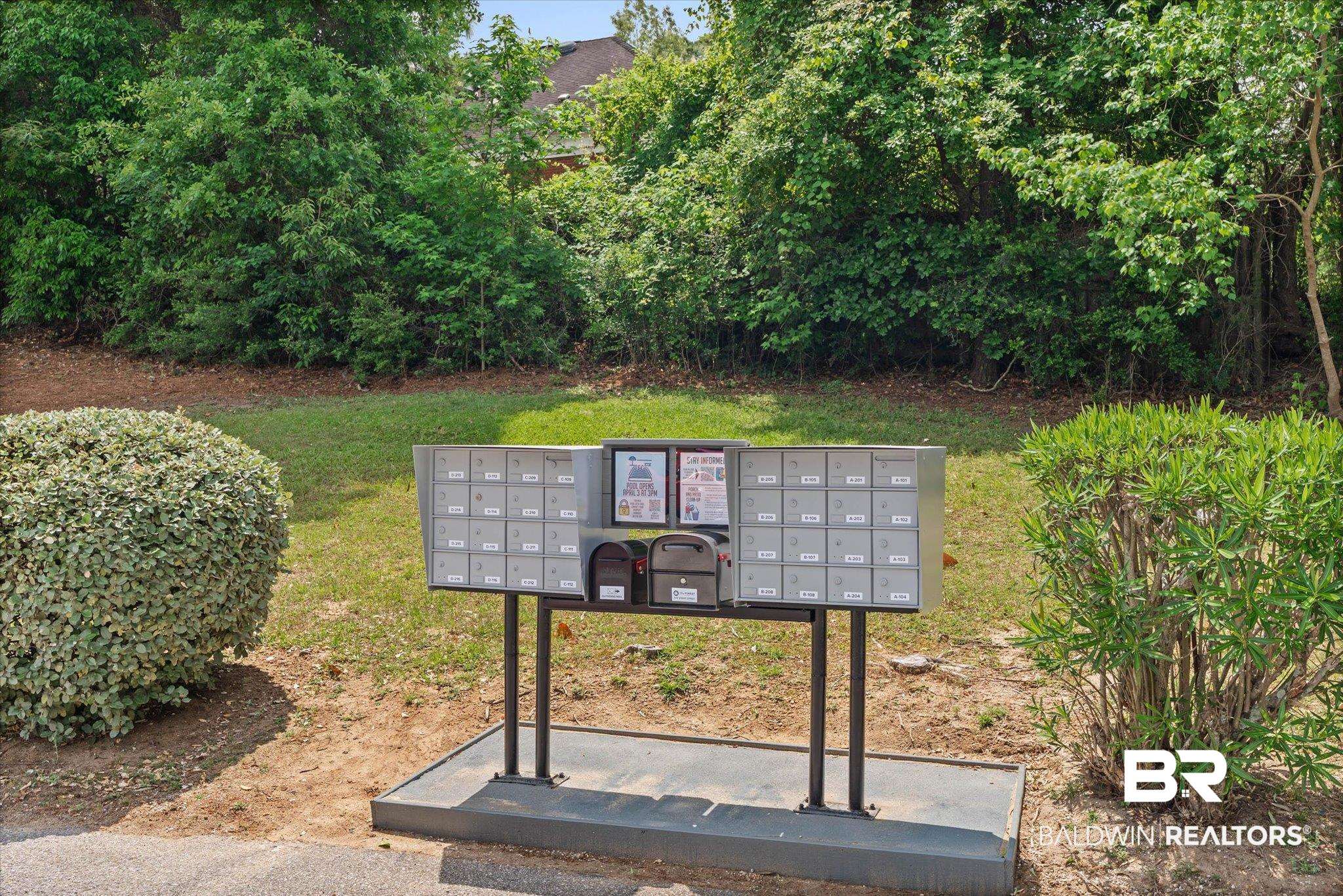 500 Grant Street, Unit D213 Daphne, AL 36526 - Photo 4 of 6 Centralized mailbox station featuring multiple individual units, two parcel lockers, and a dedicated information board