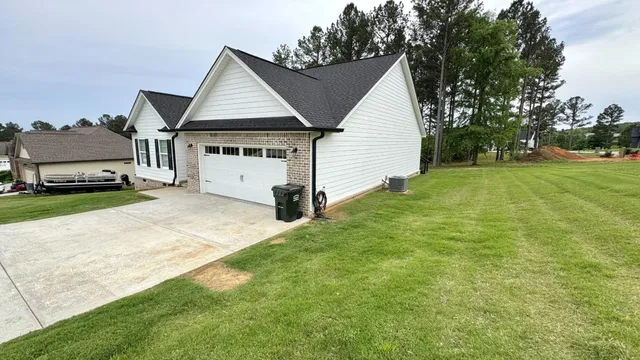 a view of a white house in front of a big yard with large trees