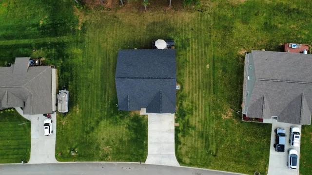 an aerial view of residential houses with outdoor space and trees