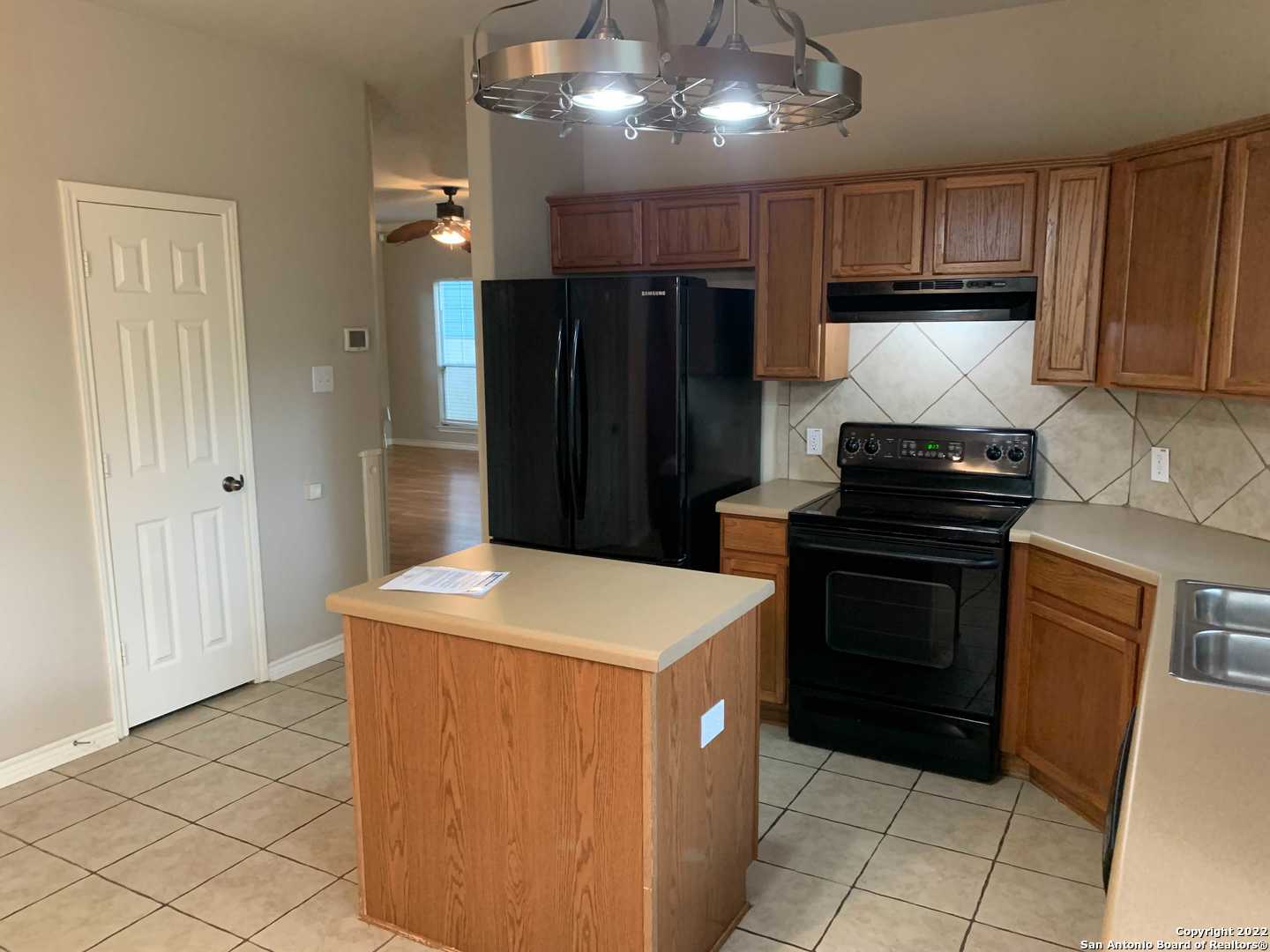 522 Cattle Ranch Drive San Antonio, TX 78245 - Photo 7 of 24 a kitchen with a refrigerator and a stove top oven