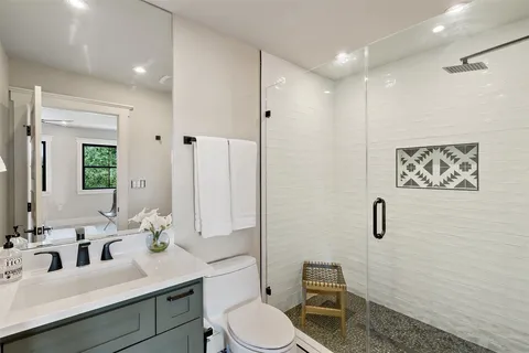 a bathroom with a toilet sink a mirror a vanity and shower