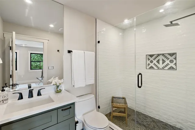 a bathroom with a toilet sink a mirror a vanity and shower