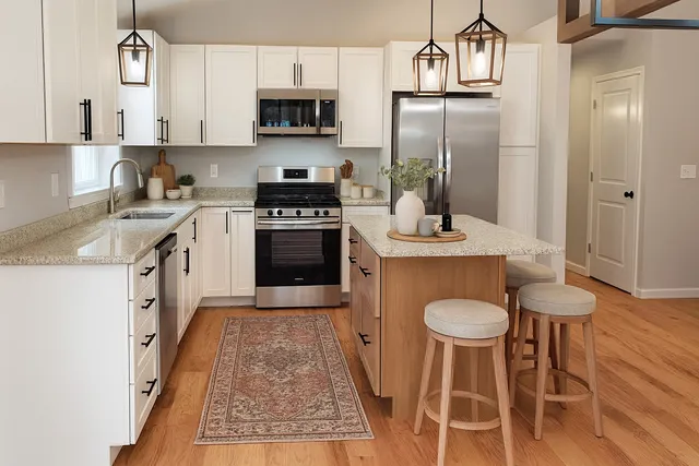 a kitchen with stainless steel appliances granite countertop a sink a stove a refrigerator cabinets and chairs