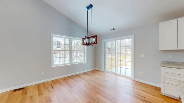 a view of an empty room with window and wooden floor