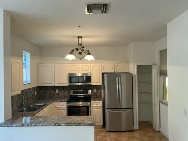 a kitchen with granite countertop stainless steel appliances a refrigerator and microwave