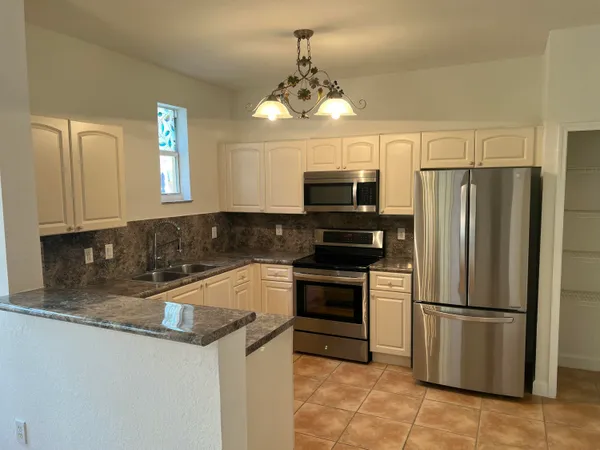 a kitchen with granite countertop a refrigerator oven a sink and dishwasher