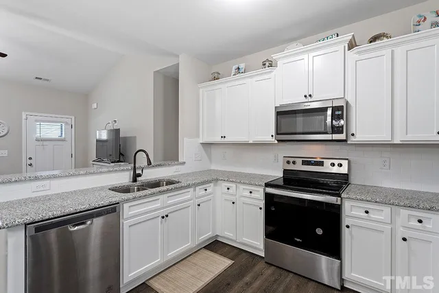 a kitchen with stainless steel appliances granite countertop white cabinets a sink and dishwasher