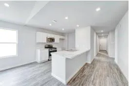 a large kitchen with stainless steel appliances kitchen island a large counter top and a wooden floors