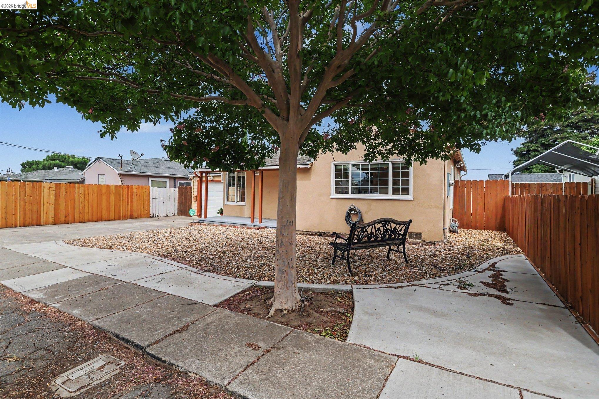 249 Madison Avenue Bay Point, CA 94565 - Photo 3 of 18 Established landscaping featuring a mature tree, gravel hardscaping, and a concrete driveway