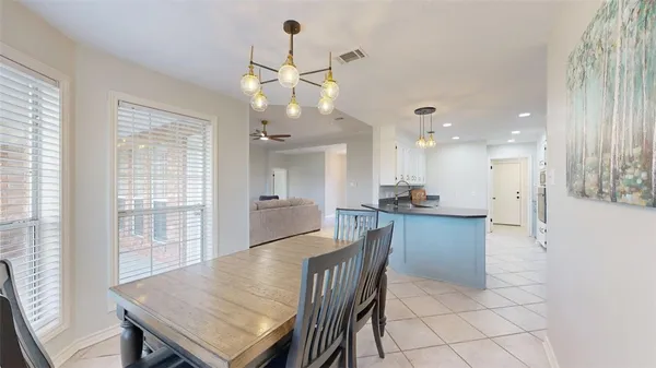 a view of a dining room and livingroom with furniture wooden floor a rug a flat screen tv a rug and a chandelier