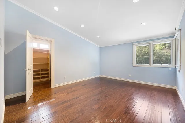 an empty room with wooden floor closet and windows