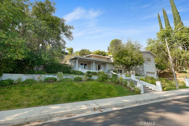 a view of a white house with a big yard and large trees