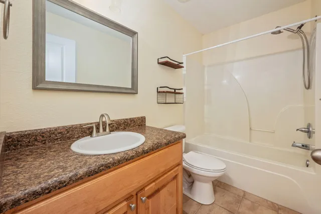 a bathroom with a granite countertop sink toilet a mirror and shower