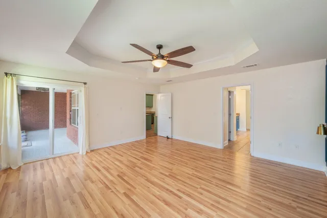 an empty room with wooden floor and a ceiling fan