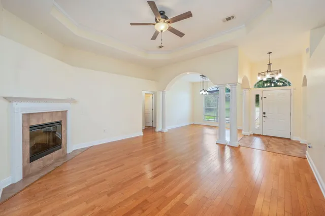 a view of an empty room with wooden floor fireplace and a window