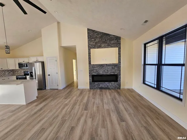 a view of empty room with kitchen and window