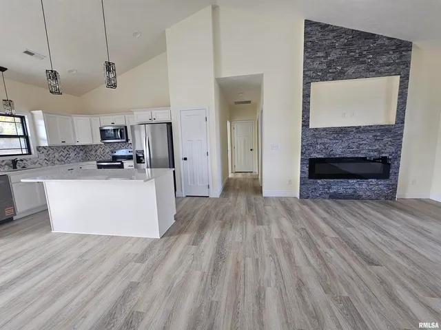 a large kitchen with stainless steel appliances granite countertop a wooden floors and view living room