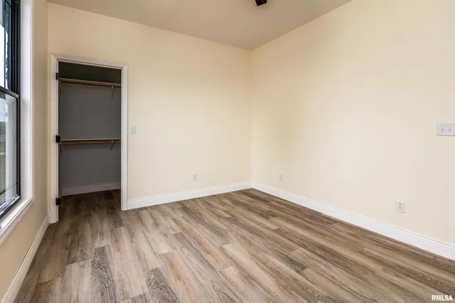 a view of an empty room with closet and a window