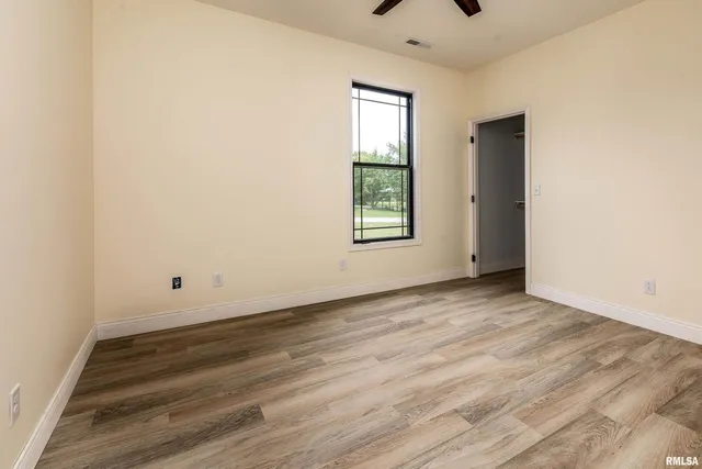 an empty room with wooden floor and windows
