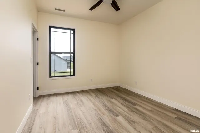 an empty room with a window and a ceiling fan