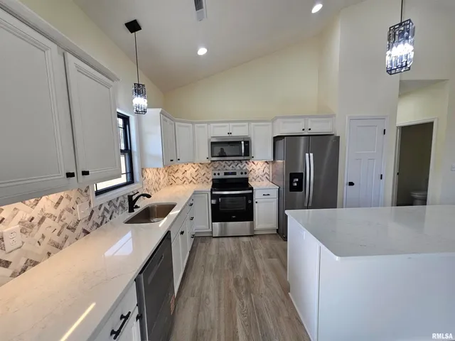a large kitchen with kitchen island a large counter space a sink appliances and cabinets