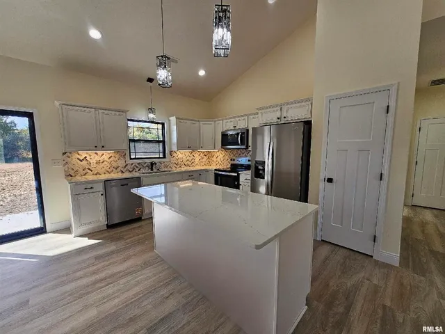 a kitchen with stainless steel appliances a refrigerator a stove a sink dishwasher and a refrigerator with wooden floor