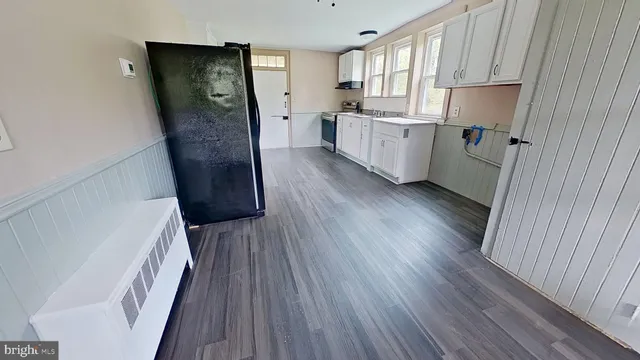 a kitchen with a refrigerator a sink and wooden floor