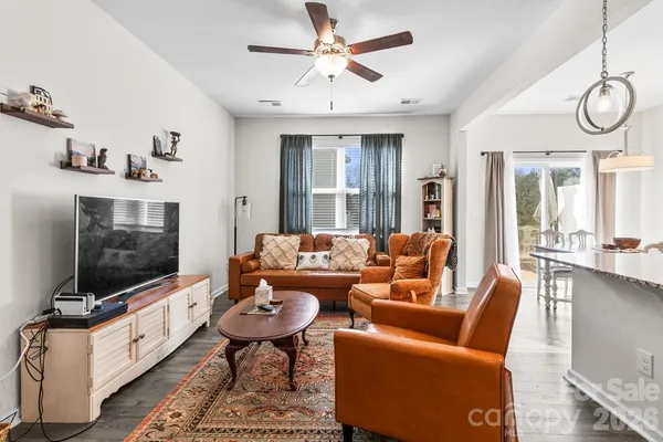a living room with furniture a flat screen tv and floor to ceiling window