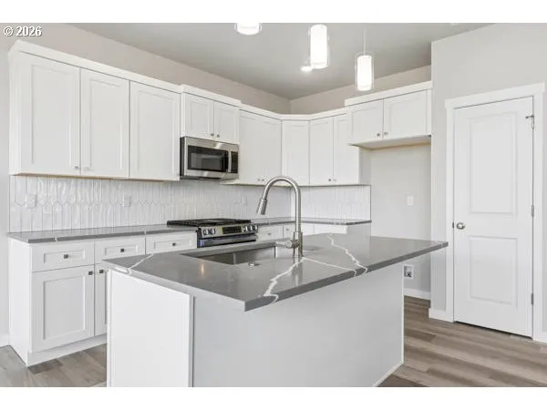 a kitchen with granite countertop a sink dishwasher a stove and a refrigerator with wooden cabinets