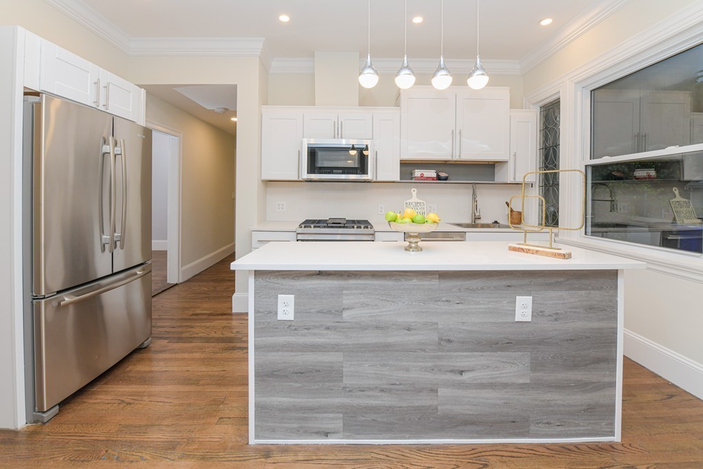 232 Aspinwall Avenue, Unit 1 Brookline, MA 02445 - Photo 5 of 13 a kitchen with kitchen island granite countertop a refrigerator oven a sink and cabinets