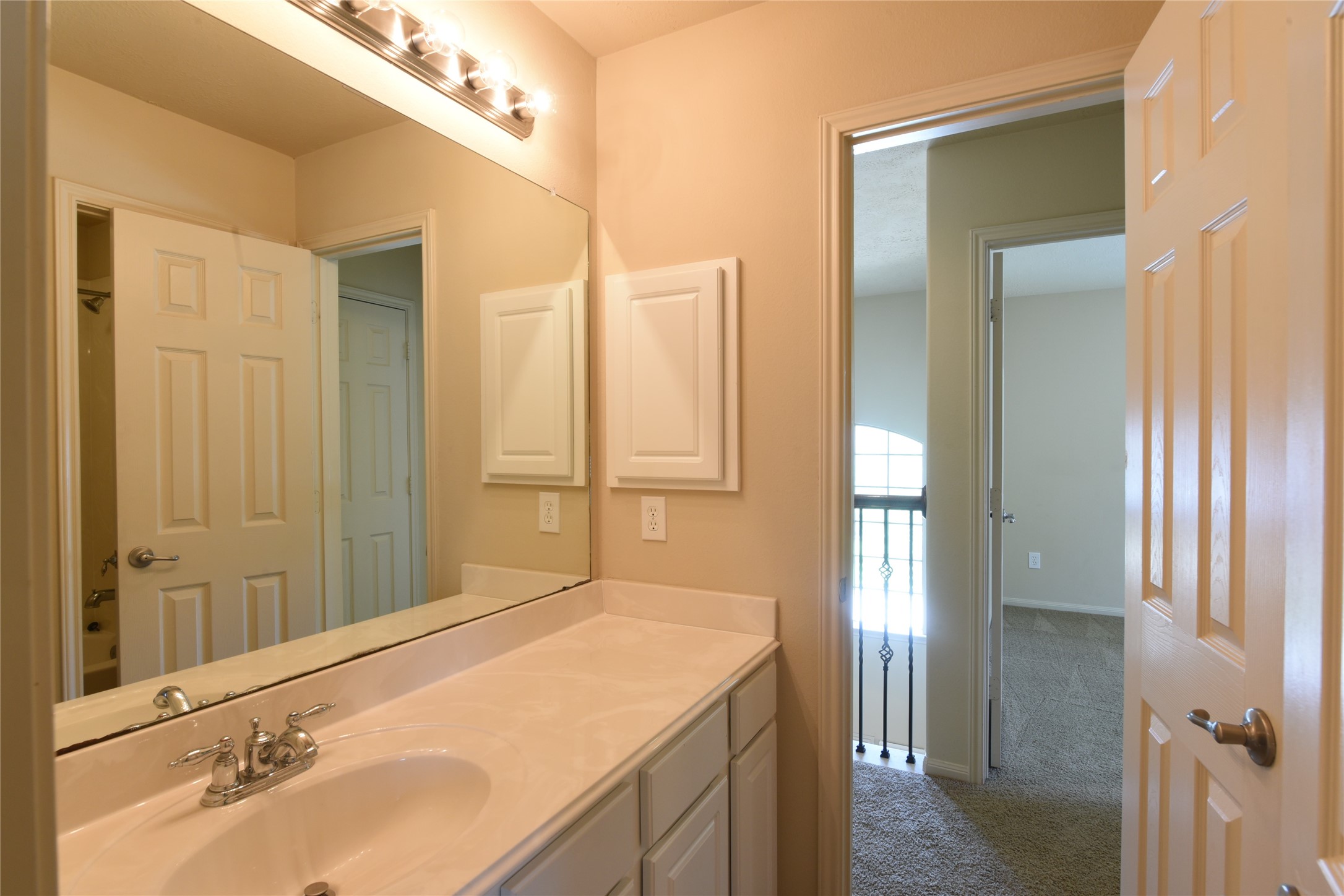 118 East Lasting Spring Circle Spring, TX 77389 - Photo 31 of 46 Modern bathroom with a single-sink vanity, ample counter space, and stylish lighting, leading to a bright, carpeted hallway.