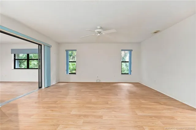 an empty room with windows and ceiling fan