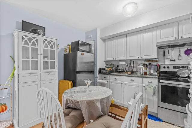 a kitchen with stainless steel appliances granite countertop a stove a sink dishwasher a refrigerator with white cabinets and wooden floor