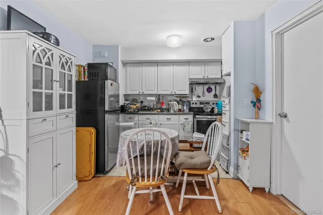 a dining room with stainless steel appliances a dining table chairs refrigerator and a sink