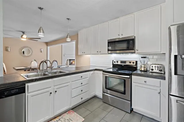 a kitchen with granite countertop white cabinets and stainless steel appliances