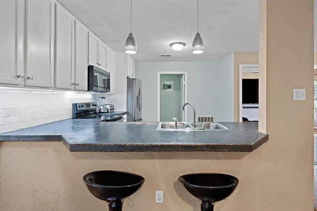 a kitchen with stainless steel appliances granite countertop a sink a stove a refrigerator a microwave oven with white cabinets and granite countertops