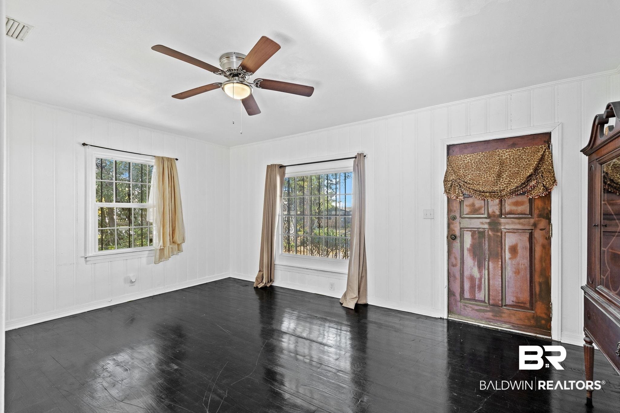 1665 Johnston Street Mobile, AL 36605 - Photo 5 of 17 Empty room with a wealth of natural light, dark wood-type flooring, and ceiling fan