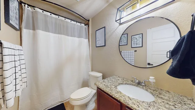 a bathroom with a granite countertop sink toilet and a mirror