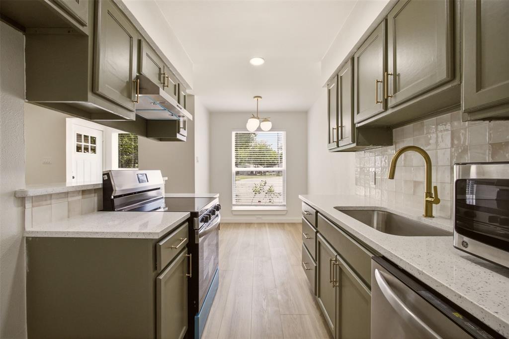908 Isbell Road, Unit B Fort Worth, TX 76114 - Photo 4 of 27 Galley kitchen featuring sage cabinetry, light-toned countertops, and an integrated stainless steel sink with a brass-finish faucet