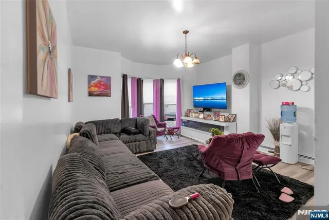 a living room with furniture a chandelier and a flat screen tv