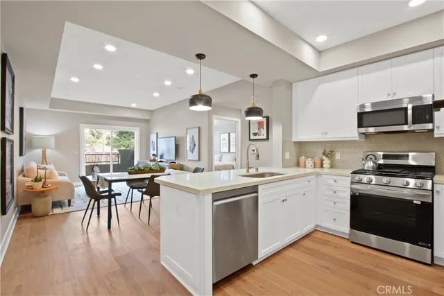 a kitchen with a sink stove and white cabinets with wooden floor