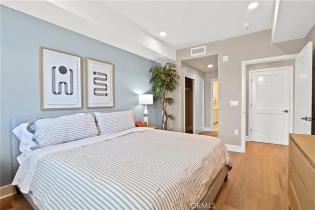 a bedroom with a large bed a painting on the wall and a potted plant