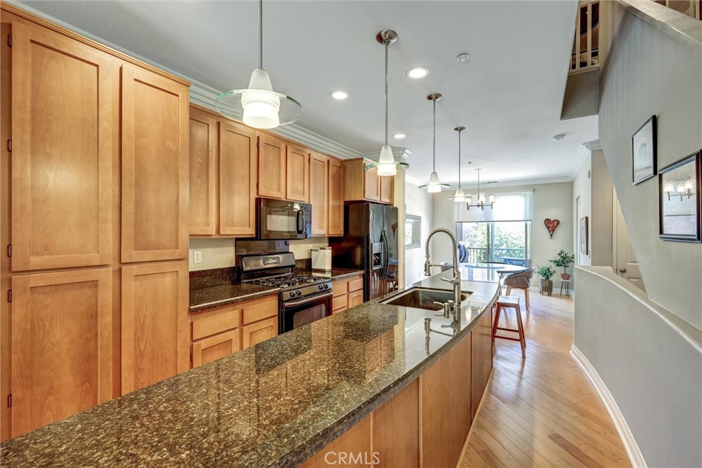 a kitchen with granite countertop a refrigerator a sink a stove top oven a dining table and chairs