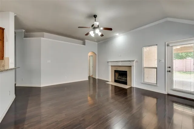 a view of an empty room with wooden floor fireplace and a window