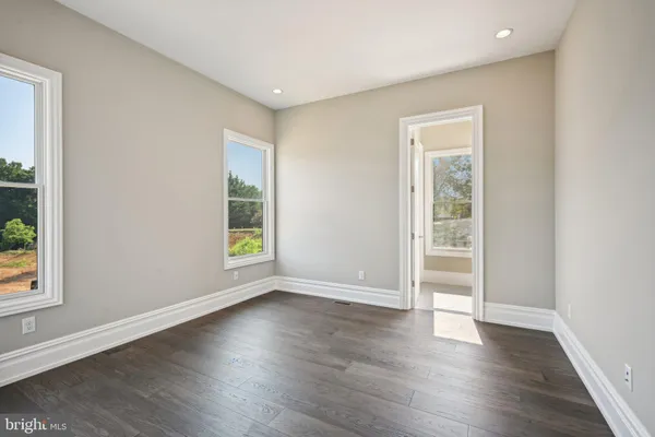 a view of an empty room with wooden floor and windows